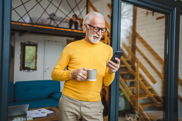 Senior Man Hold cup of coffee and Mobile Phone on Balcony happy smile