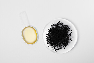 Black cumin oil in spoon and Nigella Sativa or kalonji seeds on white isolated background. The...