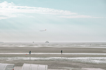  Beach activities and recreation.Kites on the wattled beach of the North Sea. Child and mother fly kites on the beach.