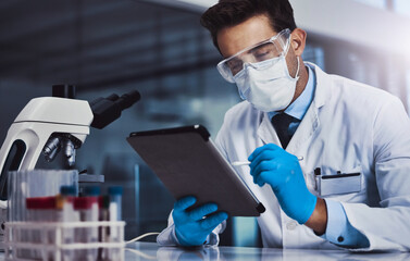 Doing online research as well. a young male scientist working in a lab.