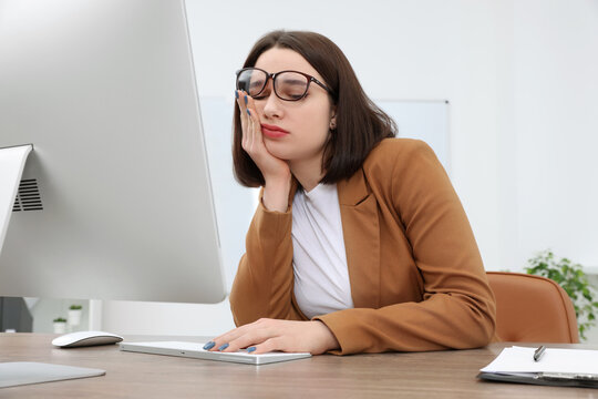 Puzzled young intern using computer at table in modern office. First work day