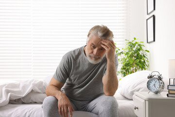 Sleepy senior man in bed at home