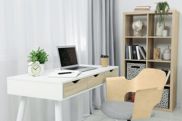 Fototapeta na wymiar Workplace with modern laptop on desk and comfortable chair at home
