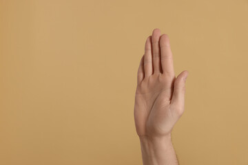 Man giving high five on beige background, closeup of hand. Space for text