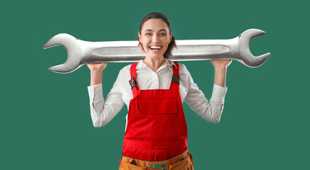 Happy female worker with big wrench on green background