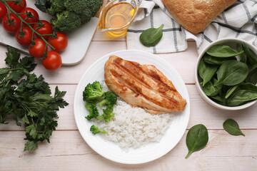 Grilled chicken breast and rice served with vegetables on wooden table, flat lay