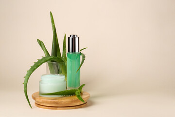 Cosmetic products and fresh aloe on beige background, space for text