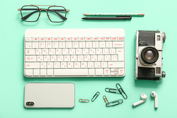 Composition with glasses, keyboard, mobile phone and photo camera on turquoise background
