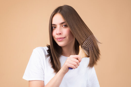Portrait of charming brunette hair lady combing hair with hairbrush comb, isolated.