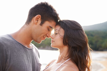 Blissful summer days together. A young couple sharing a romantic moment while on a beach.