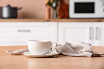 Saucer with cup and napkin on wooden table in kitchen