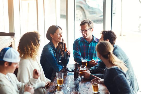 The favorite Friday hangout spot. a group of friends enjoying some beers at a bar.