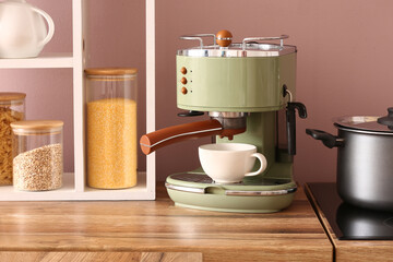 Modern coffee machine with cup on wooden kitchen counter