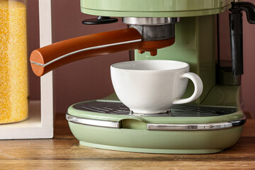Modern coffee machine with cup on wooden kitchen counter, closeup