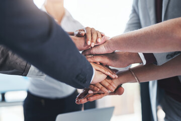 Their hard work really adds up. a group of unrecognizable businesspeople piling their hands on top of each other in the office.