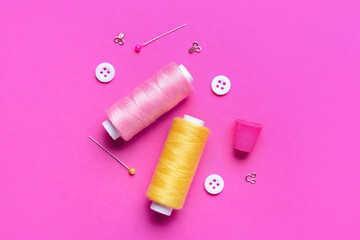 Composition with thread spools and sewing supplies on pink background