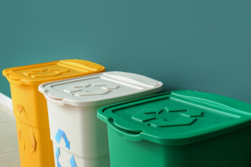 Different garbage bins with recycling symbol near green wall
