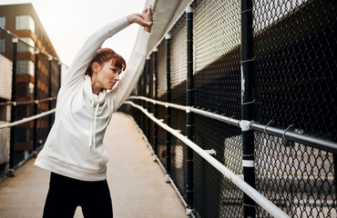 Fototapeta premium She never runs before stretching. an attractive young woman stretching before her run in the city.