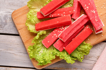 Board with tasty crab sticks on light wooden background © Pixel-Shot