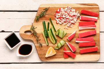 Board with tasty crab sticks and sauces on light wooden background © Pixel-Shot