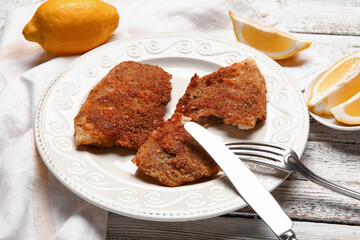 Plate of tasty fried codfish on light wooden background