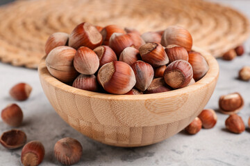 Bowl with shelled hazelnuts on grey grunge background