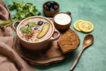 Pot of tasty Hodgepodge soup with sour cream and bread on grunge background