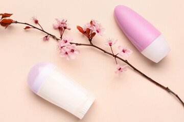 Deodorants with flowers and blooming branch on beige background