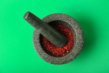 Mortar and pestle with spices on green background