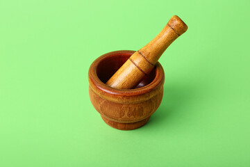 Wooden mortar and pestle on green background