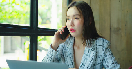 Beautiful asian woman working in restaurant. She using smartphone to talk with team.