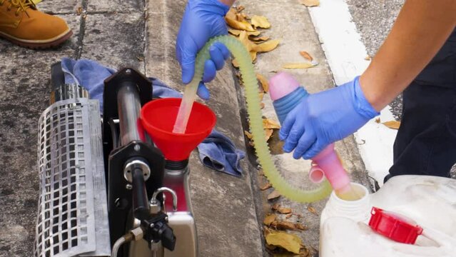 Worker preparing fogging service by pouring chemical insecticides into machine, Southeast Asia