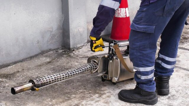 Slow motion of worker starting fogging service with insecticides spraying machine