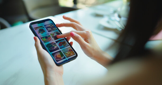 Woman using phone to looking menu in restaurant.
