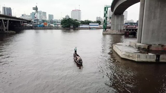 Fishermen on a pirogue in the Lagos lagoon near a bridge. Nigeria