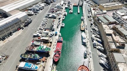 Drone aerial shot pulling back over several ships in a boat yard revealing a wide view of the ship yard