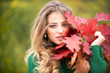 Autumn portrait of cheerful woman with yellow maple leaves. Portrait of beauty girl with autumn leafs on foliage. Close up portrait of a beautiful girl near autumn leaves. Romantic tenderness woman.