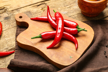 Board of fresh hot chili peppers on brown wooden background