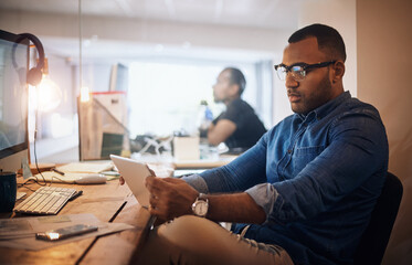 Making a few smart connections during his late shift. a young businessman using a digital tablet in an office at night.