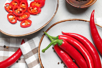 Plate and bowl with fresh chili peppers on table, closeup