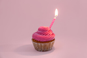 Tasty cupcake with birthday candle on pink background
