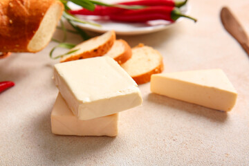 Processed cheese with bread and herbs on light grunge background