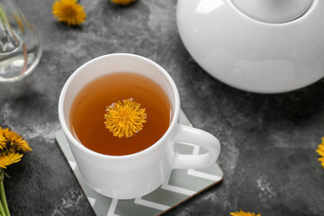 Cup of healthy dandelion tea on grey background