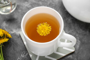 Cup of healthy dandelion tea on grey background