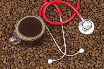 Coffee affects blood pressure and heart health concept. Coffee cup and red stethoscope on roasted coffee beans.