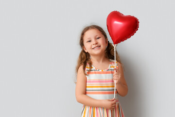 Little girl with heart shaped balloon on light background. Children's Day celebration