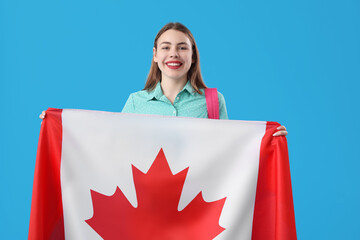 Young woman with flag of Canada on blue background