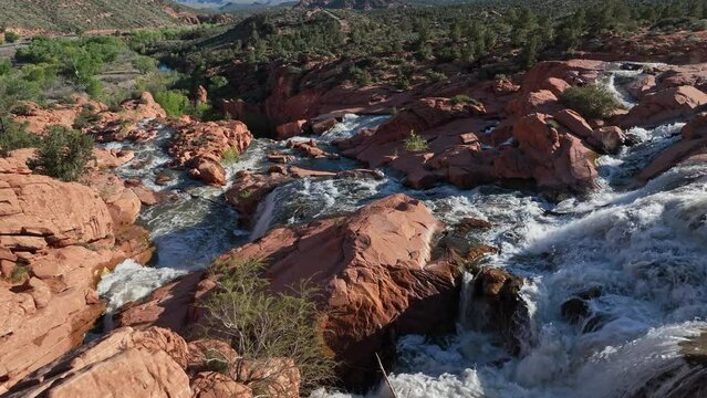 Aerial view flying down Gunlock Waterfalls flowing downstream over the red rocks in Southern Utah.