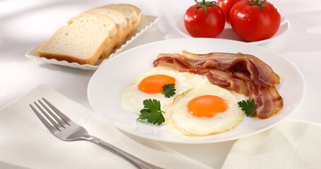 fried eggs with bacon on a plate. breakfast with fresh vegetables and bread on the table. sunny morning. country style. organic farm food