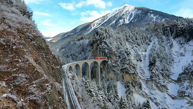 Bernina express in Swiss Alps snow winter scenery Red train passing through famous mountain in Filisur, Switzerland.Taken from an action camera
